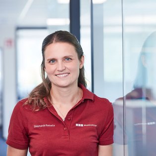 Mitarbeiterin in rotem T-Shirt schaut in die Kamera