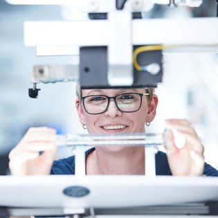 Mitarbeiterin bedruckt ein Glasvolumenmessgeraet