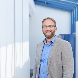 Mann schaut in die Kamera und laechelt